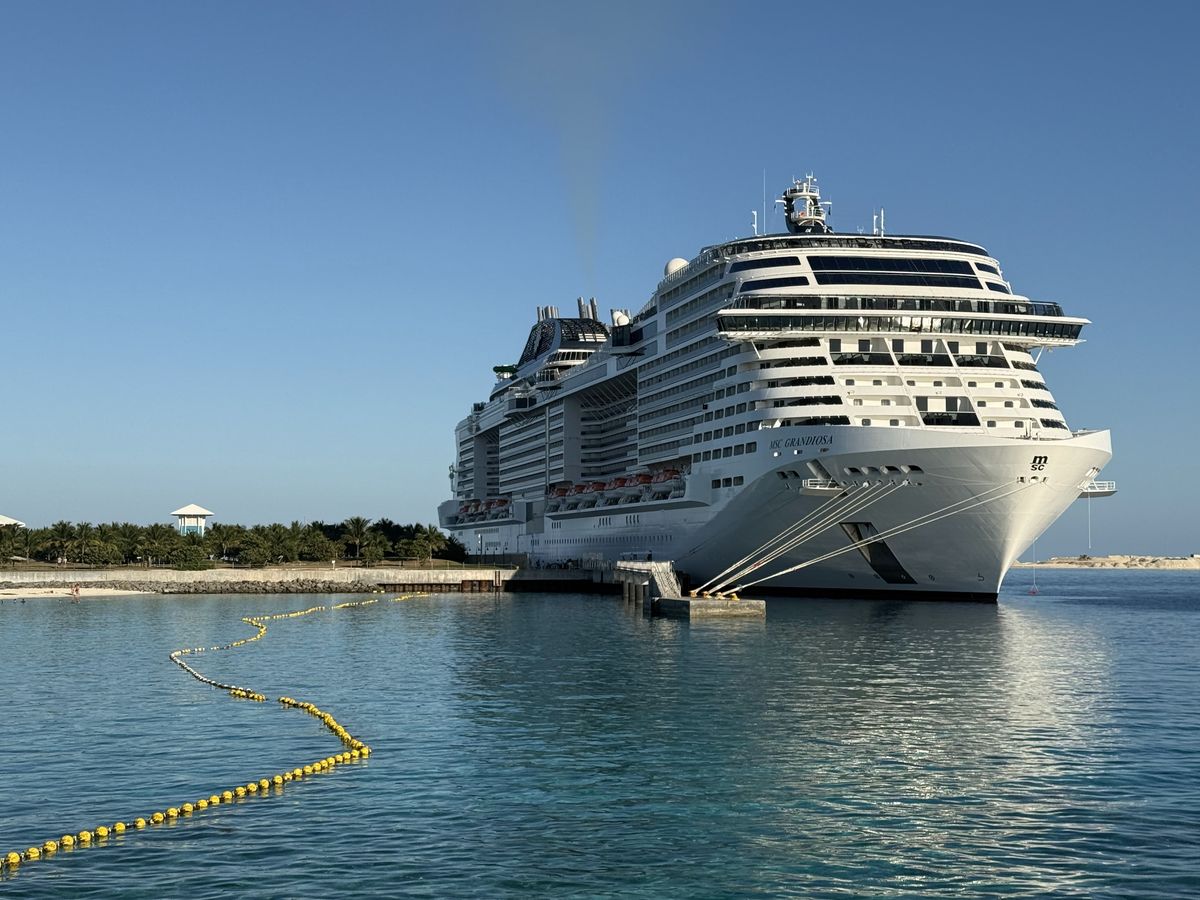 The cruise ship MSC Grandiosa docked at Ocean Cay under a clear blue sky.