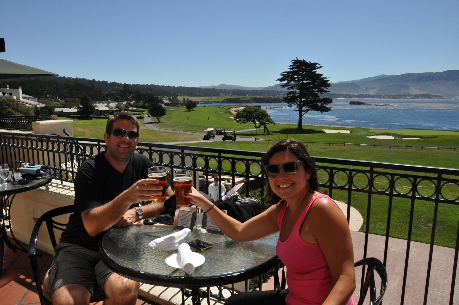Bill and Carrolyn raise glasses of beer at a terrace table overlooking the 18th green and Carmel Bay at Pebble Beach, California, in 2012.
