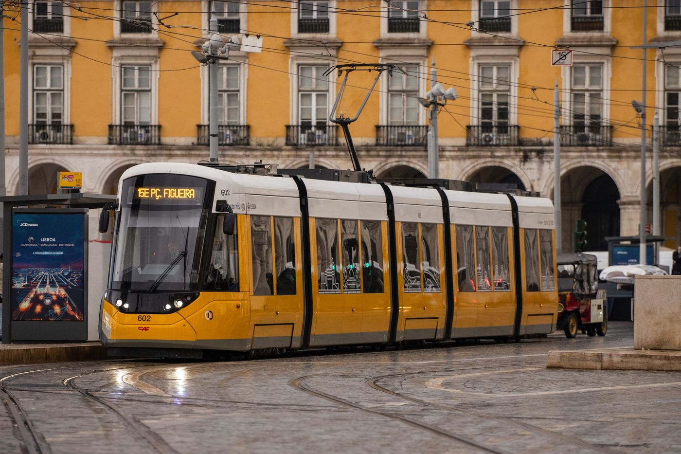 Yellow tram passing yellow arcaded buildings in downtown Lisbon